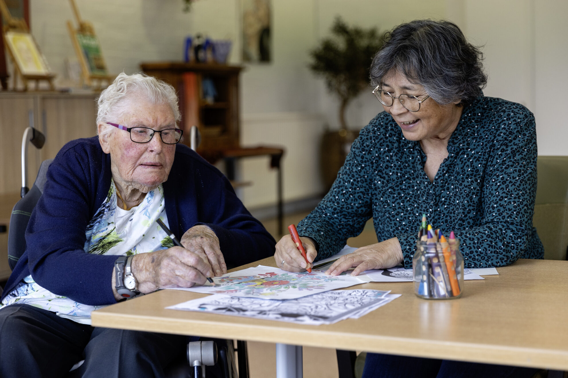 Audrey kleurt met een oudere dame in Woon- en zorgcentrum De Marke in Bergen
