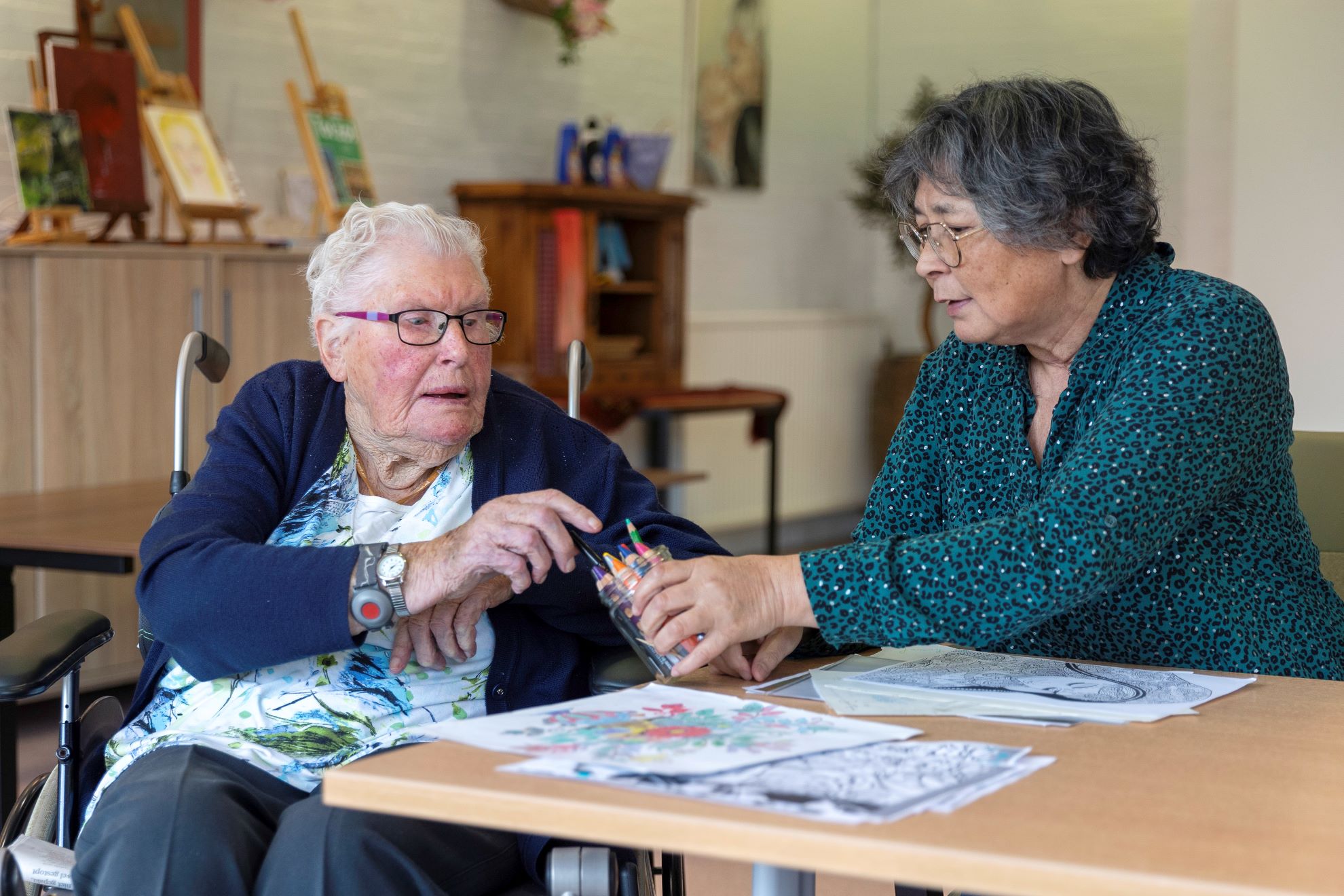 Audrey kleurt met een oudere dame in Woon- en zorgcentrum De Marke in Bergen